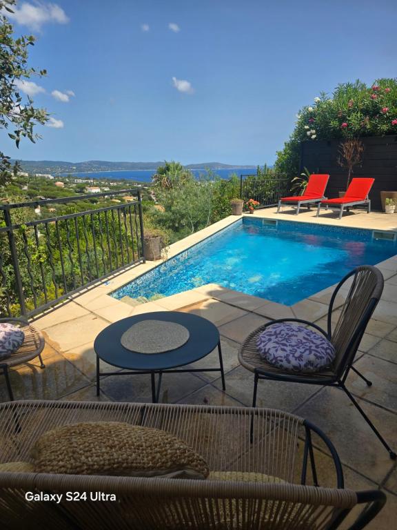 a swimming pool with chairs and tables next to at La lézarde in Cavalaire-sur-Mer