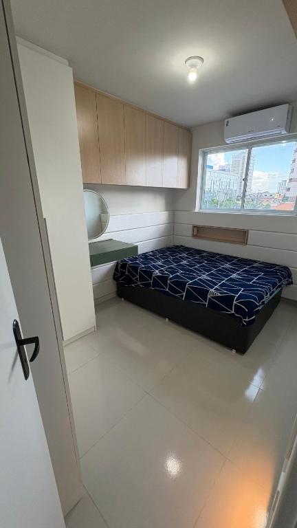 a small room with a bed and a window at Flat Eufrates 205 in Olinda