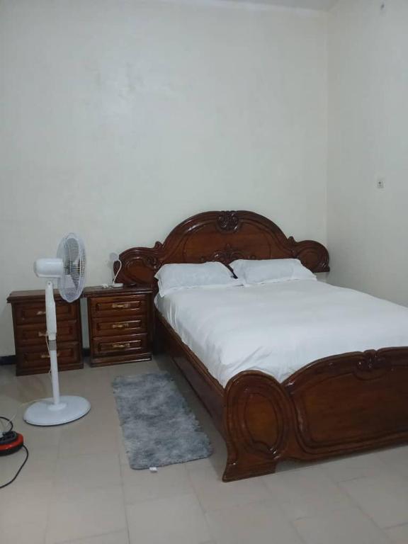 a bedroom with a large wooden bed and a fan at Chez ABDOUL in Rufisque