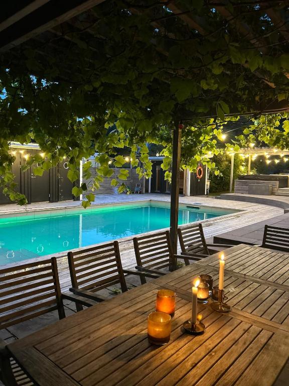 a wooden table with candles on it next to a swimming pool at Villa Circus in Halmstad