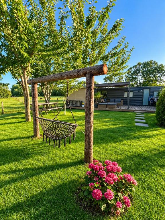 a swing in the middle of a yard with flowers at De Polderhoeve in Heerhugowaard