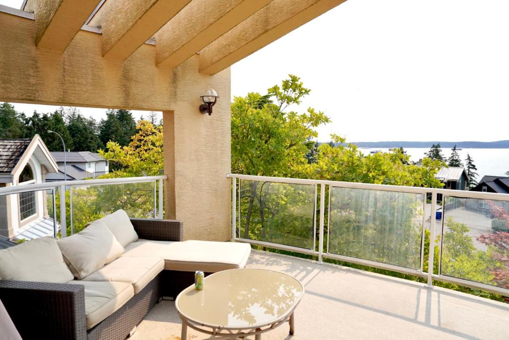 a patio with a couch and a table on a balcony at The Shearwater House - Panoramic Ocean View Suites in Nanaimo