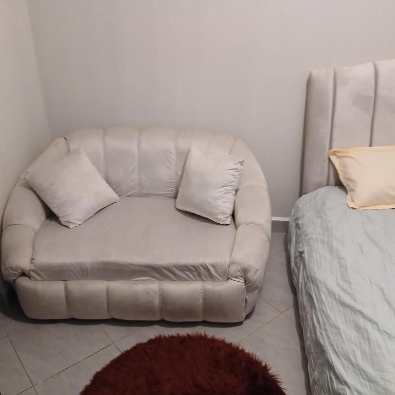 a couch with two pillows sitting next to a bed at Studio apartment at Arc Residence in Nairobi
