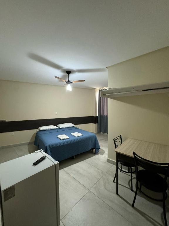 a bedroom with a bed and a desk and a table at Neves Hotel II in Ipatinga