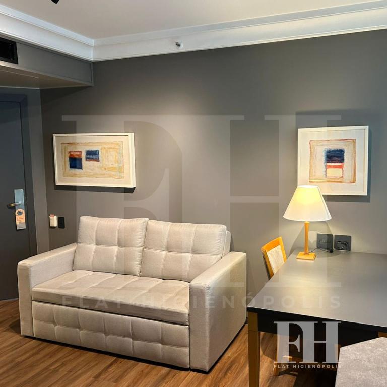 a living room with a white couch and a table at Flat Higienópolis in São Paulo