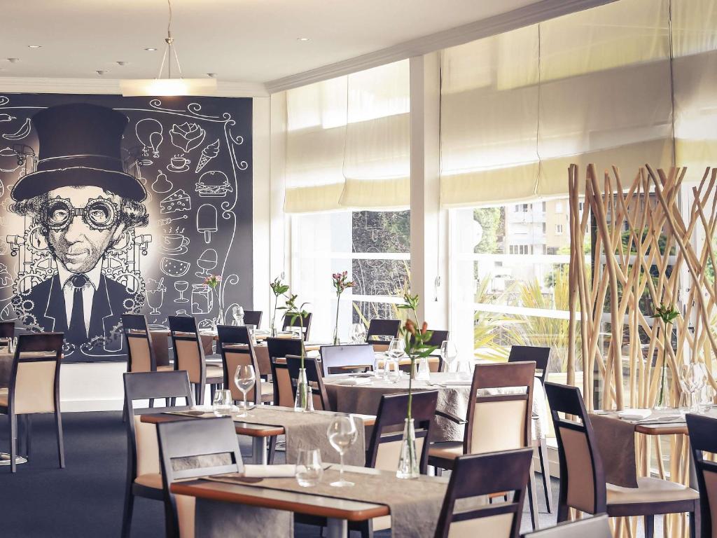 ein Restaurant mit Tischen und einem Gemälde eines Mannes mit Zylinderhut in der Unterkunft Mercure Saint Lô Centre in Saint Lo