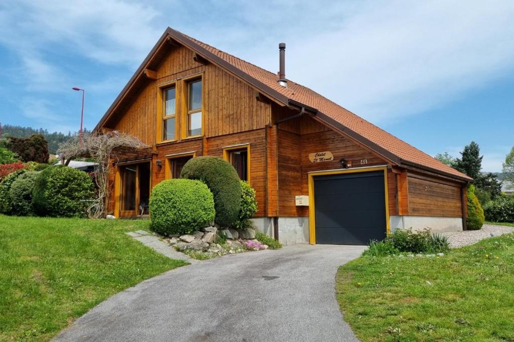 a wooden house with a garage on a driveway at Chalet avec mezzanine 4 étoiles, Saint Mamet, jusqu'à 10 couchages, proche du lac de Gérardmer des commerces et des pistes de ski dans un quartier calme in Gérardmer
