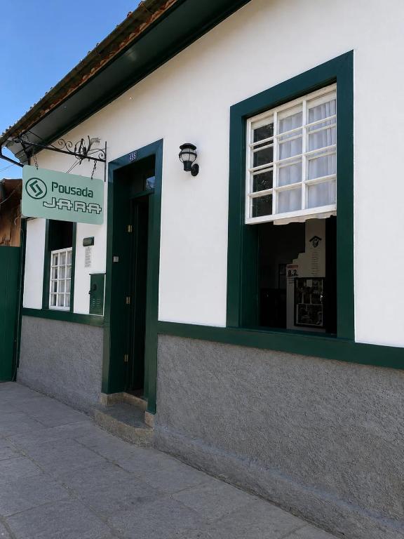 a building with a green door and a window at Pousada Jara in Conservatória