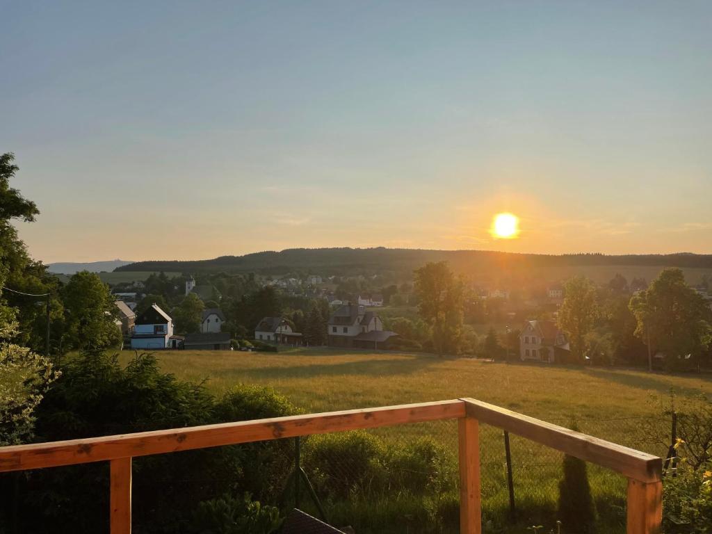 a sunset over a field with a wooden railing at Kovářská vyhlídka in Kovářská