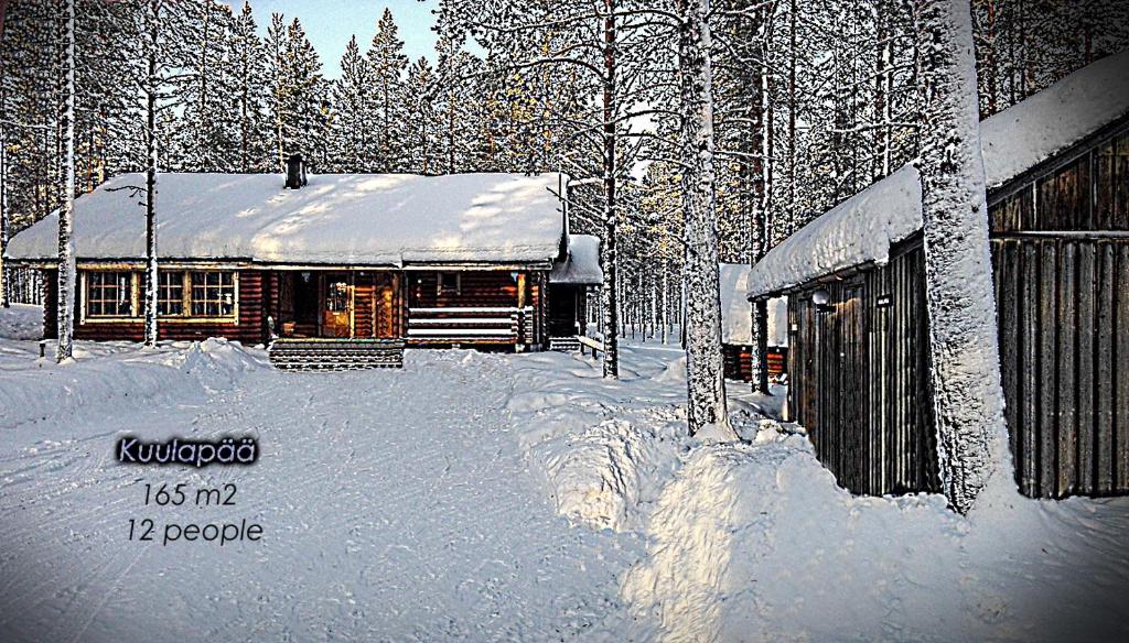 une maison recouverte de neige à côté d'un bâtiment dans l'établissement Kuulapää Chalet, à Äkäslompolo