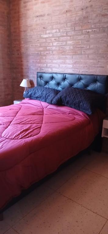 a large bed with a red comforter in a room at lo de la Gri in El Volcán