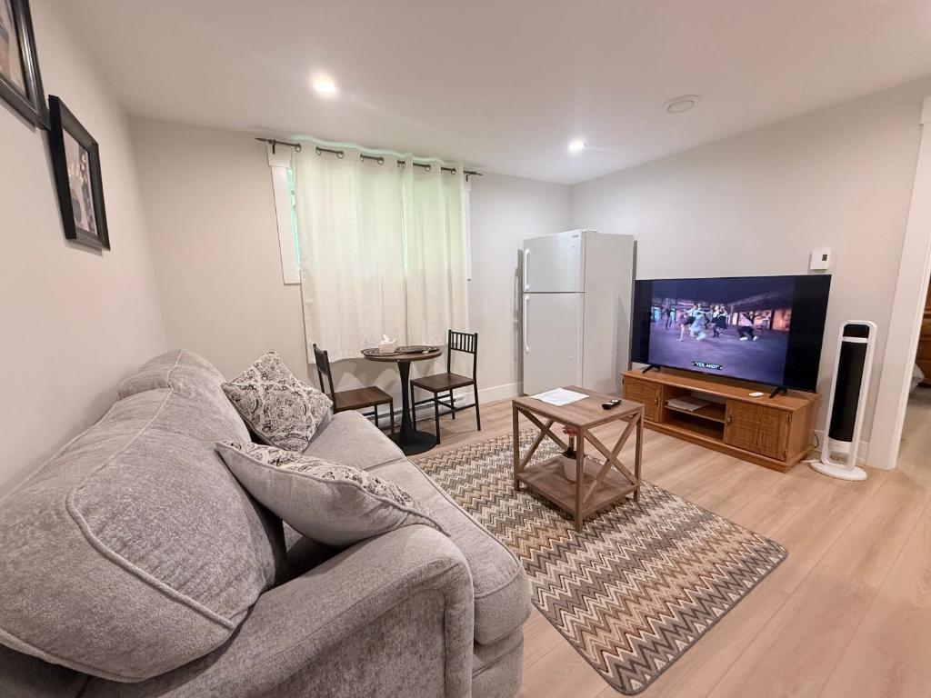 a living room with a couch and a flat screen tv at Befitting Crown Suite in Moncton
