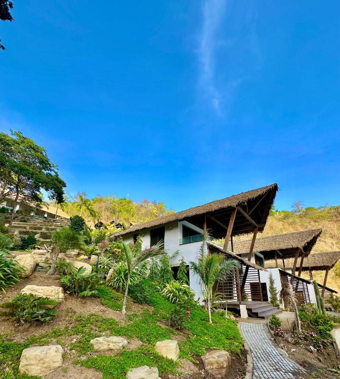 a white house with a thatched roof at Bliss Resort in San Juan del Sur