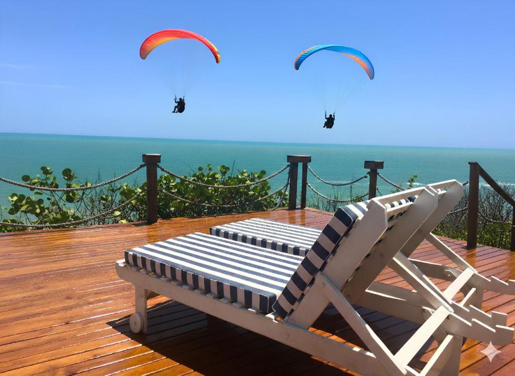 a deck with a chair and kites flying over the ocean at Pousada Azul Marinho in Canoa Quebrada