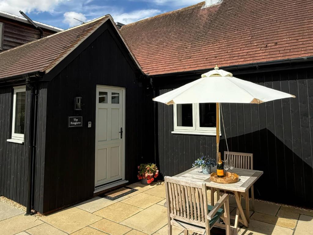 a black shed with a table and an umbrella at Foxglove in Bicester