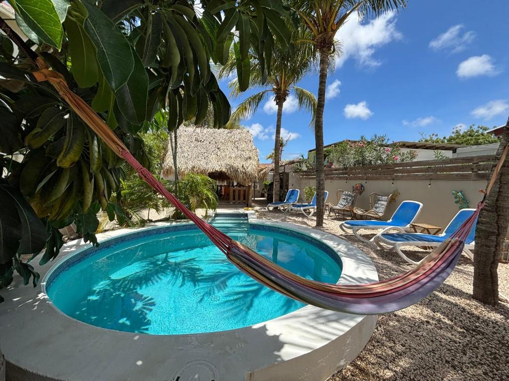 a hammock by a swimming pool in a resort at BnBBonaire near the ocean in Kralendijk