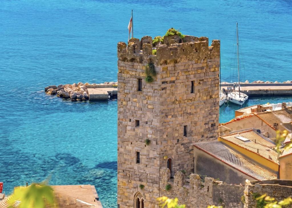 Eine Burg mit einer Flagge darauf, direkt am Meer in der Unterkunft Capitolare Tower in Porto Venere