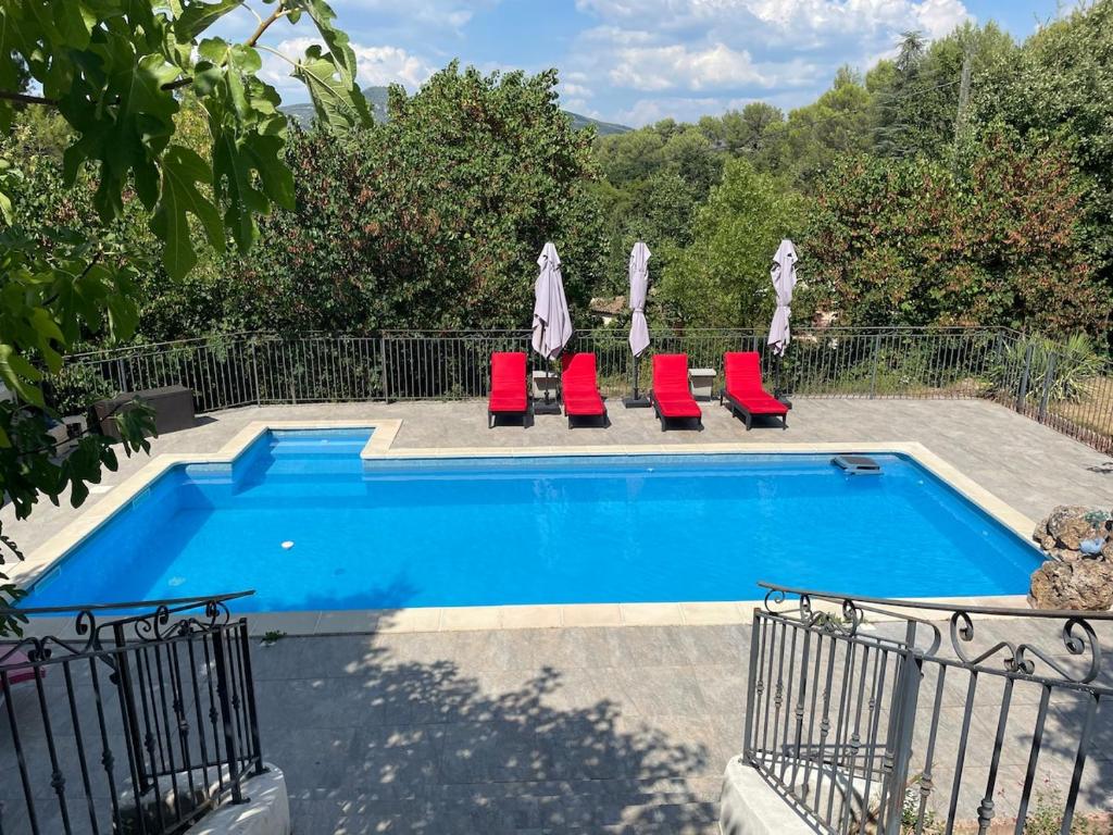 a swimming pool with red lounge chairs next to it at Appartement tout confort à Auriol in Auriol