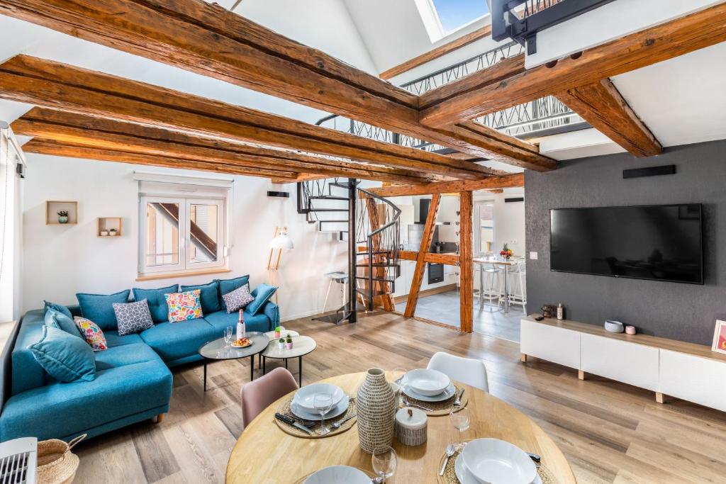 a living room with a blue couch and a tv at Le Bartholdi in Andolsheim