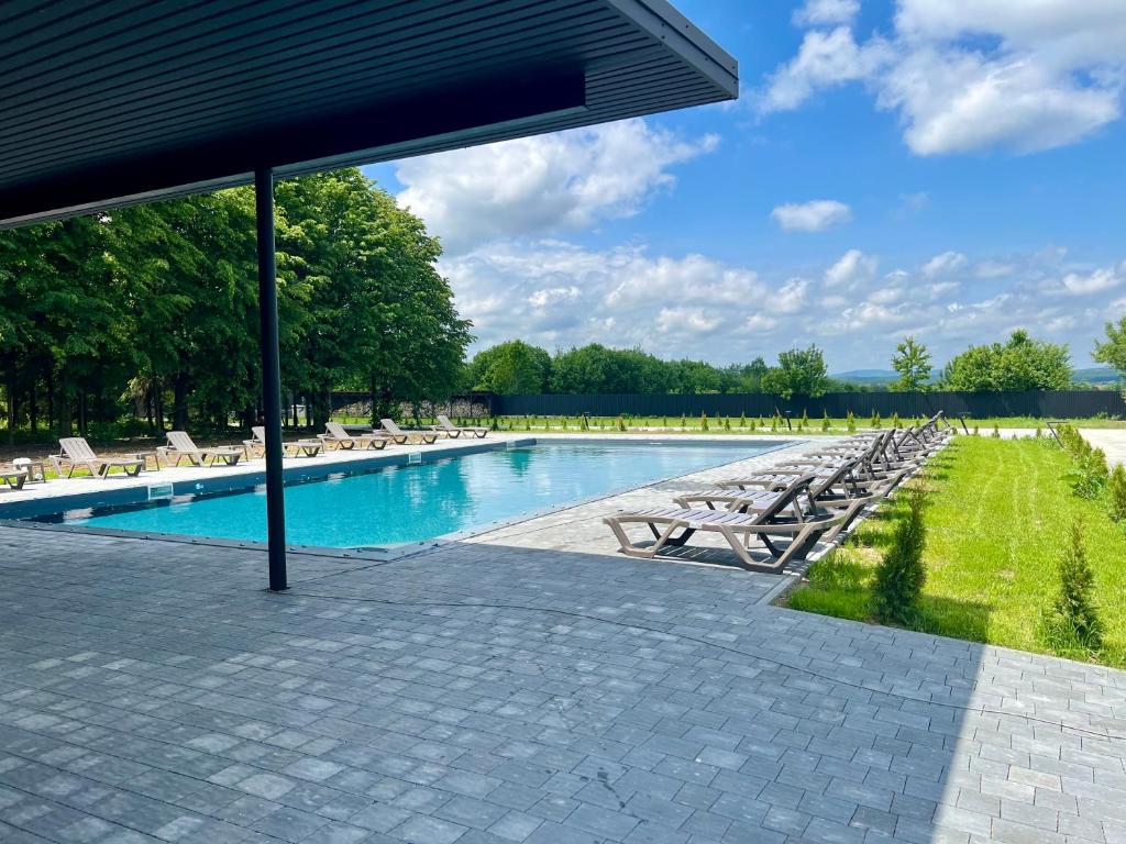 a swimming pool with lounge chairs and an umbrella at Маєток на Озерах in Ispas