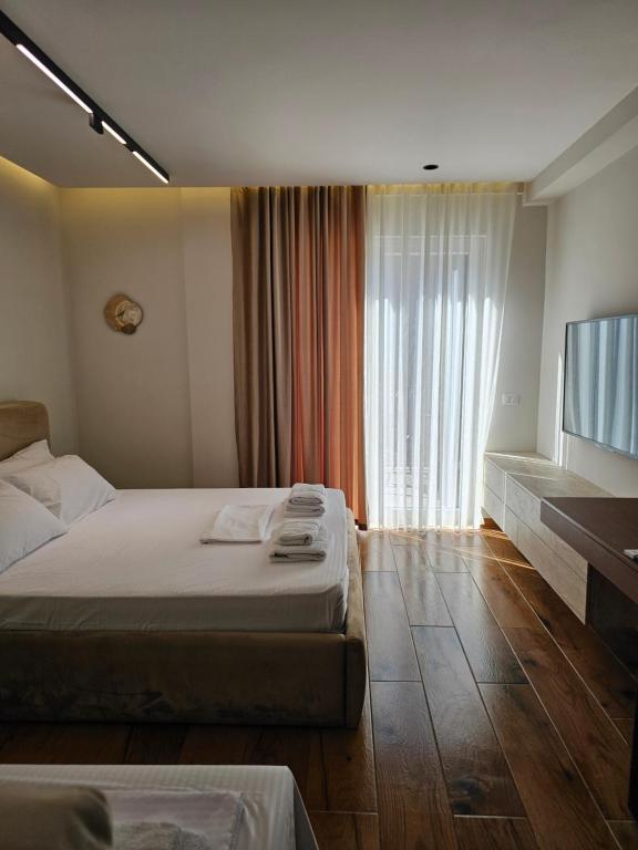 a hotel room with two beds and a flat screen tv at Dejvid's Apartment in Dhërmi