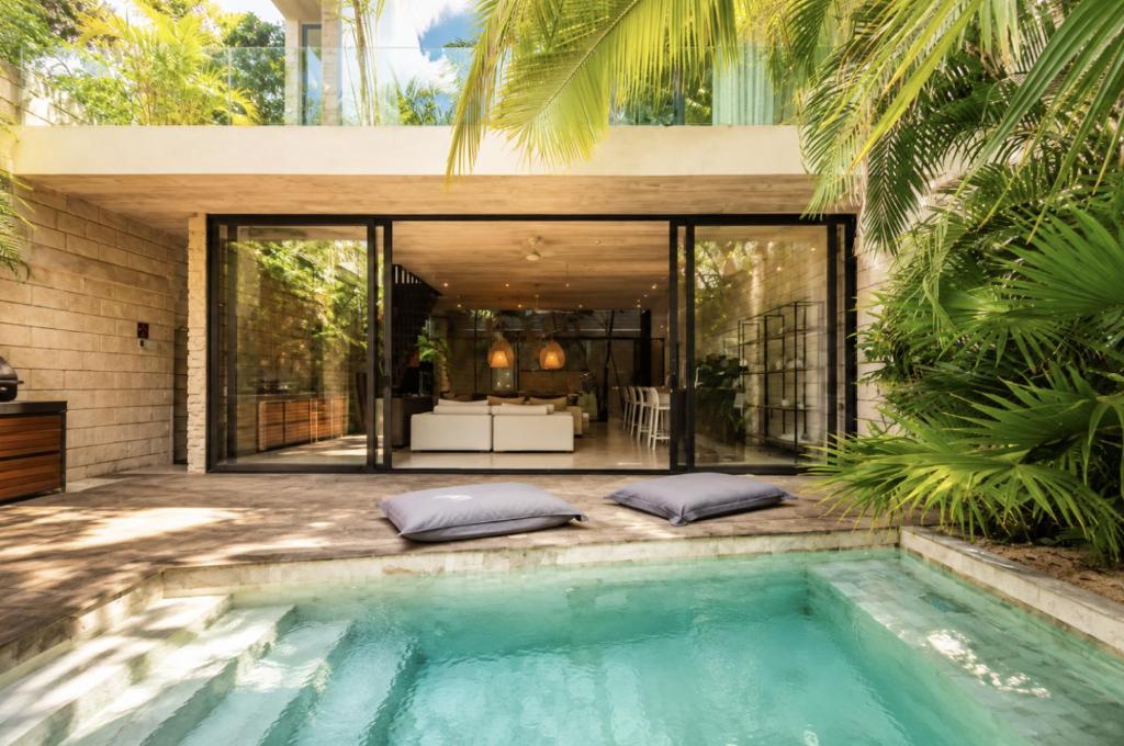 a swimming pool in front of a house at Hum Living Luxury Villas in Tulum