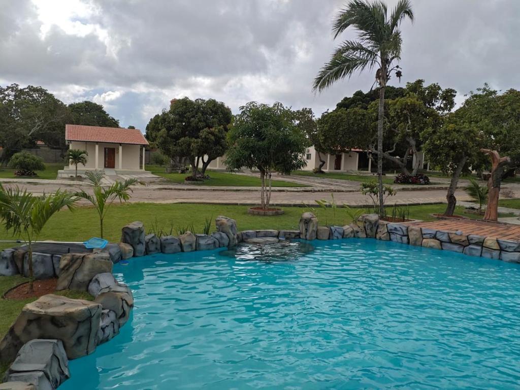 a swimming pool in a yard with a rock wall at Chalés Sítio Frade in Martins