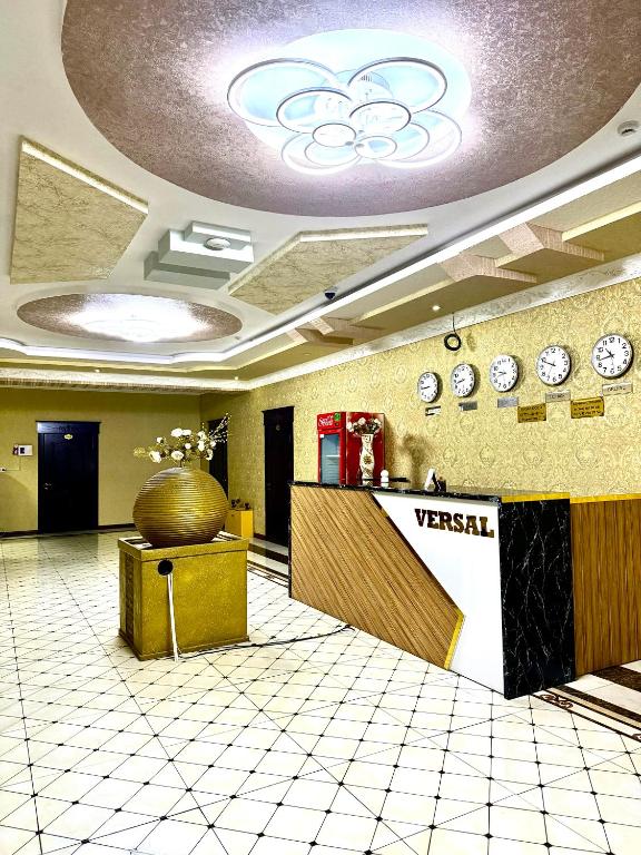 a lobby with a waiting area with clocks on the wall at Версаль отель in Türkistan
