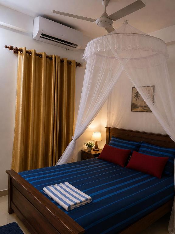 a bedroom with a canopy bed with blue sheets and red pillows at SunBeachHouse in Weligama