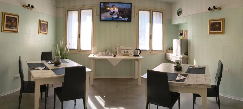 a dining room with two tables and a tv on the wall at La Casa di Giovanni B&B in Romano D'Ezzelino