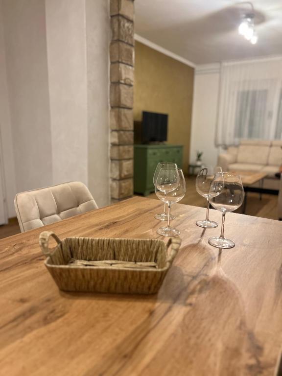 two wine glasses and a basket on a wooden table at Garden View Apartment in Čapljina