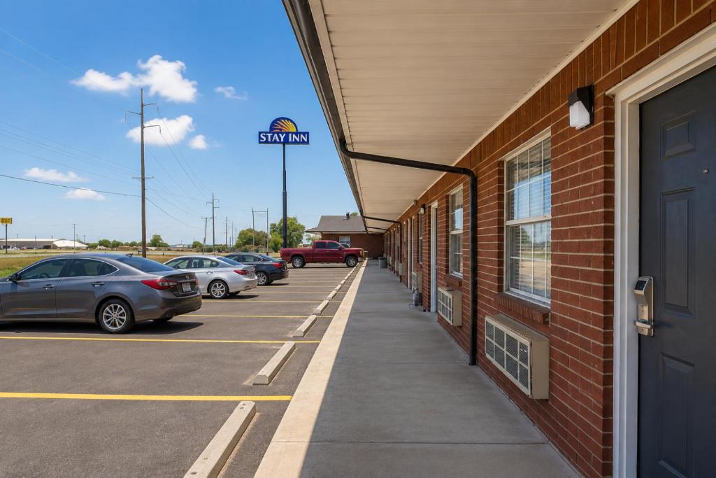 a building with cars parked in a parking lot at Stay Inn Checotah near Eufaula Lake in Checotah
