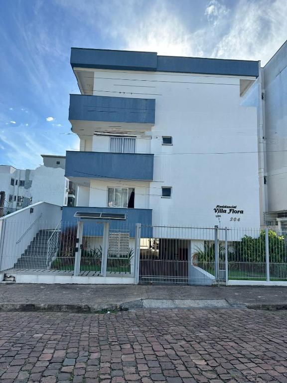 a white building with a fence in front of it at Apartamento Unisc in Santa Cruz do Sul