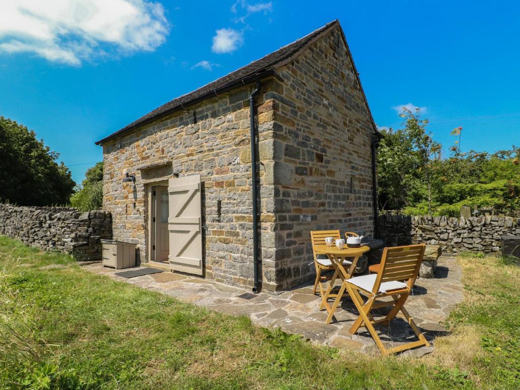 a stone cottage with a table and chairs in front of it at Little Barn in Leek