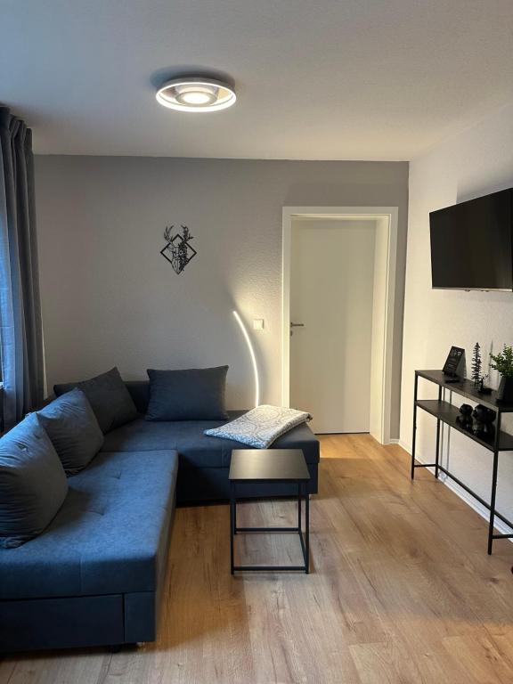 a living room with a blue couch and a table at Ferienwohnung zum Buchhellertal in Burbach
