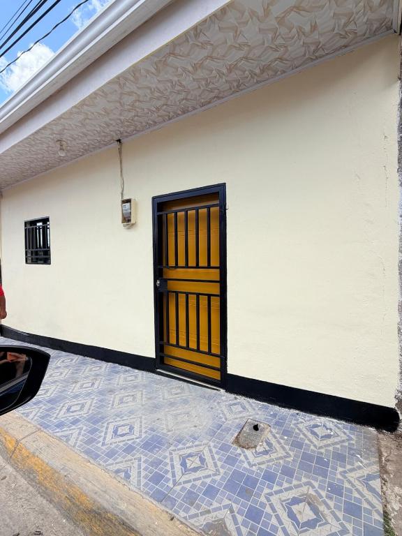 a white building with a wooden door on it at The Cozy House in Estelí
