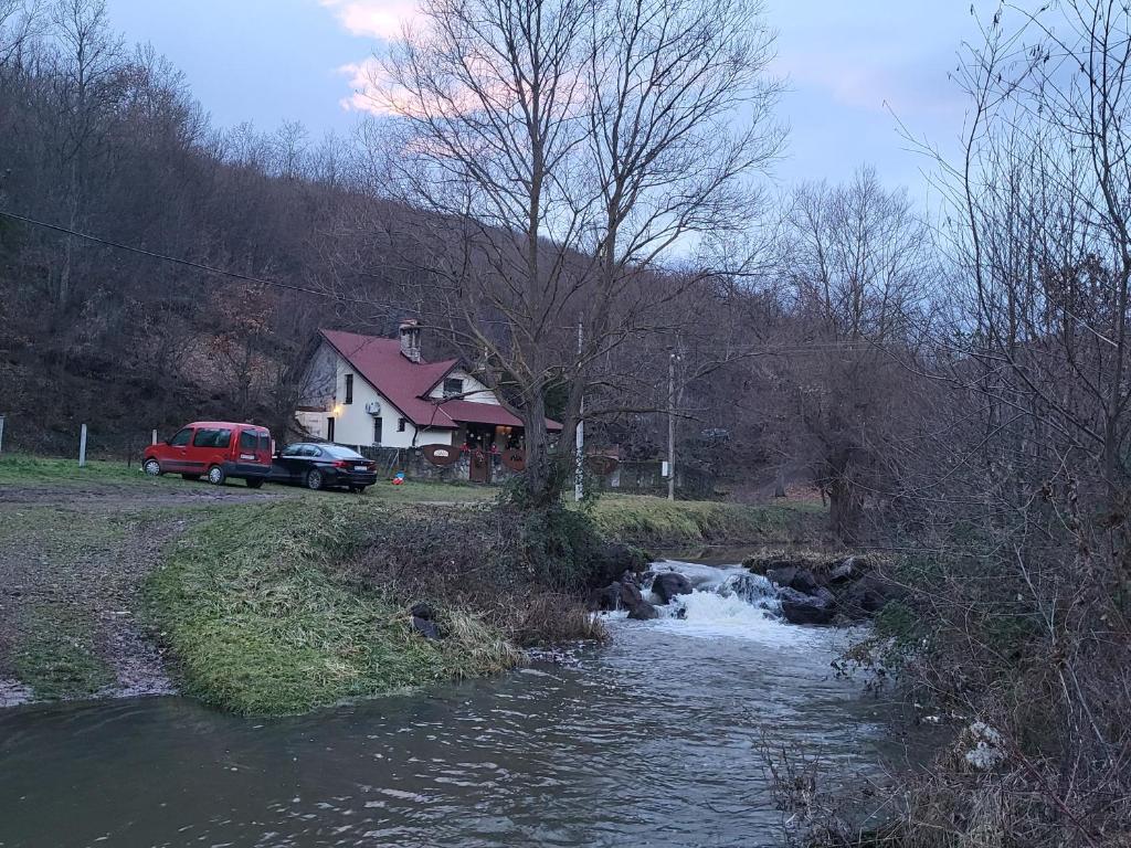 a house with a red truck parked next to a river at Deda Mrazova kućica in Knić
