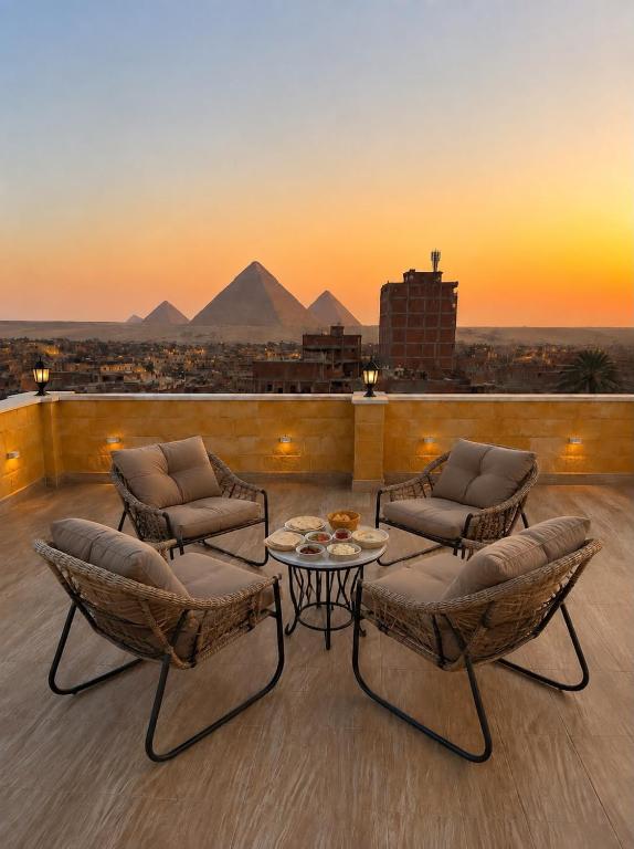 a rooftop patio with chairs and a table and pyramids at Royal Pyramids Hotel in Cairo