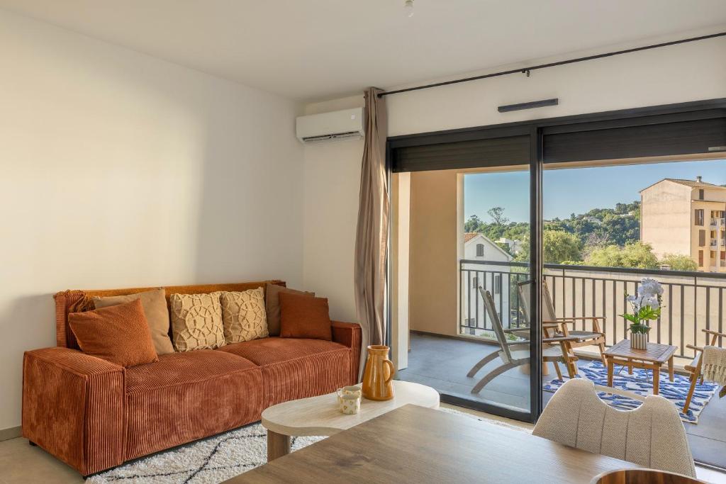 a living room with a couch and a balcony at Le Cocon d'Orezza - Appart Climatisé avec Balcon in Penta-di-Casinca