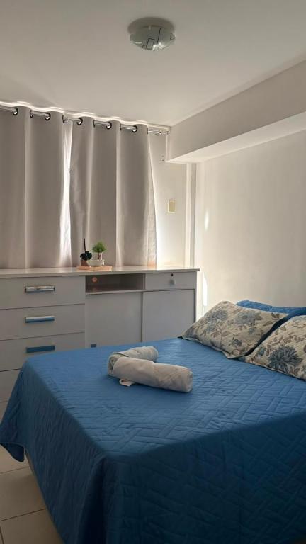 a bedroom with a bed with a blue blanket and a kitchen at Prive in Paulista