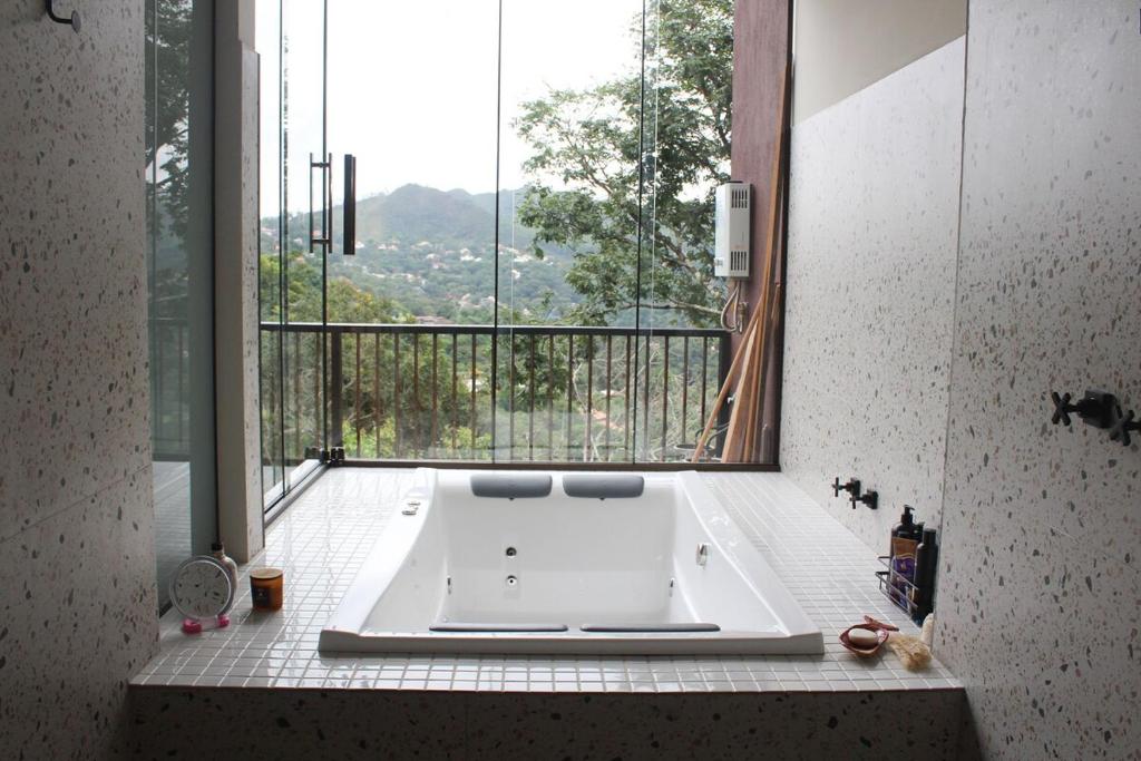 a bath tub in a bathroom with a large window at Loft Montclair in Nova Lima