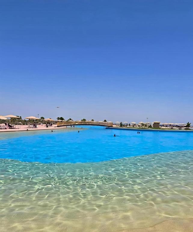 ein großer Pool mit blauem Wasser neben einem Strand in der Unterkunft Lagoon Blumar Hotel Chalet in Ain Suchna