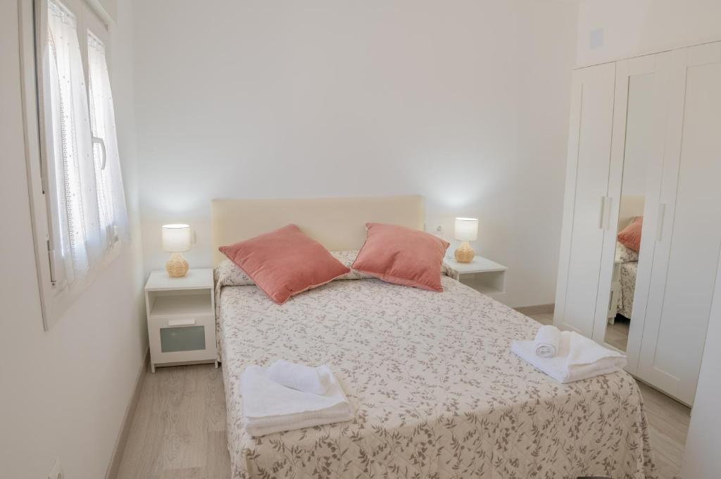 a white bedroom with a bed with pink pillows at Apartamento Aira in Villadepalos