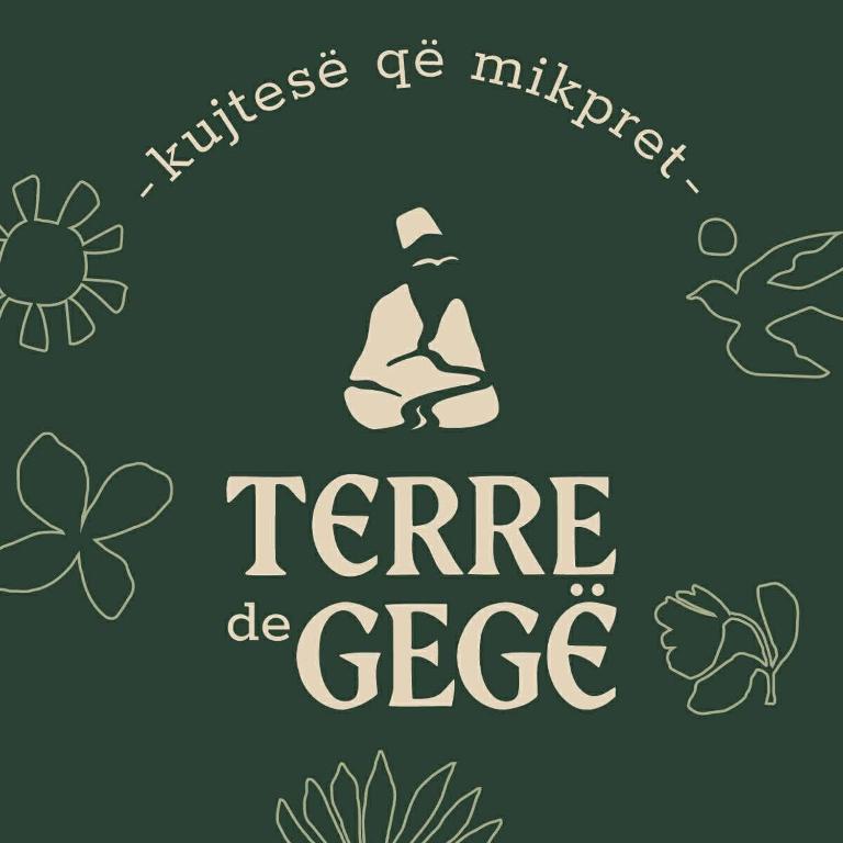 a sign that reads ferre be glee with a bottle and flowers at Terre de Gegë Hotel in Kukës