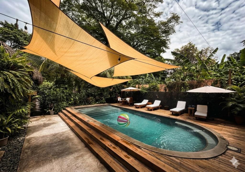 a swimming pool with a large umbrella over it at Hotel Michanti in El Zonte