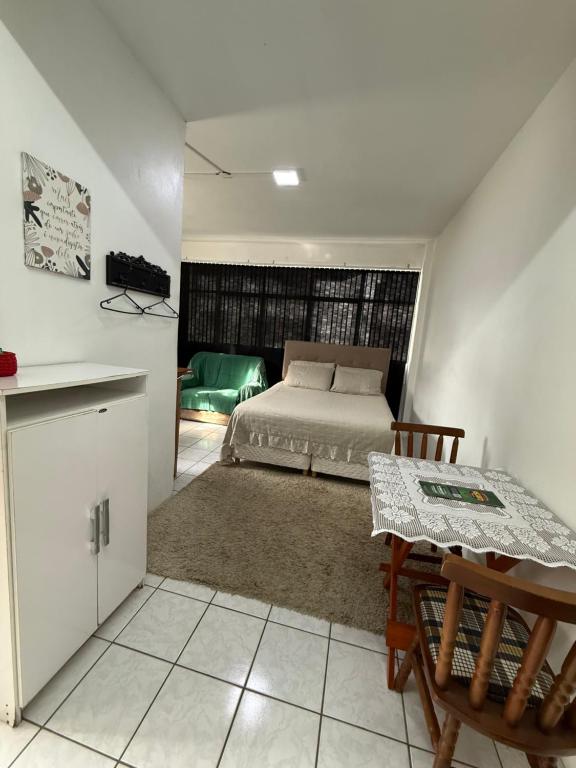 a bedroom with a bed and a table in it at KITNETS Kretzer Hinckel 1 - CENTRO in Alfredo Wagner