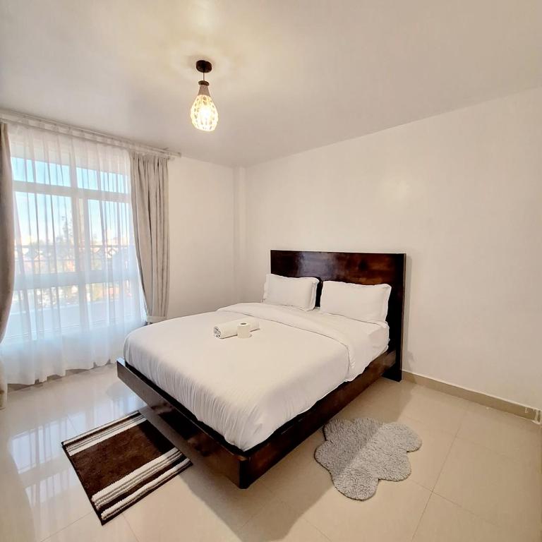 a bedroom with a large bed with a large window at Collins unique apartments in Ruaka