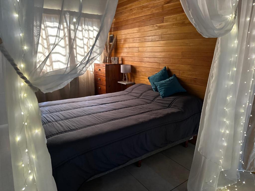 a bedroom with a bed with curtains and lights at Refugio Viggena in Tandil