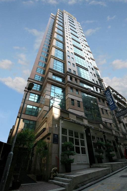 a tall building with glass windows on a city street at Shama Central in Hong Kong
