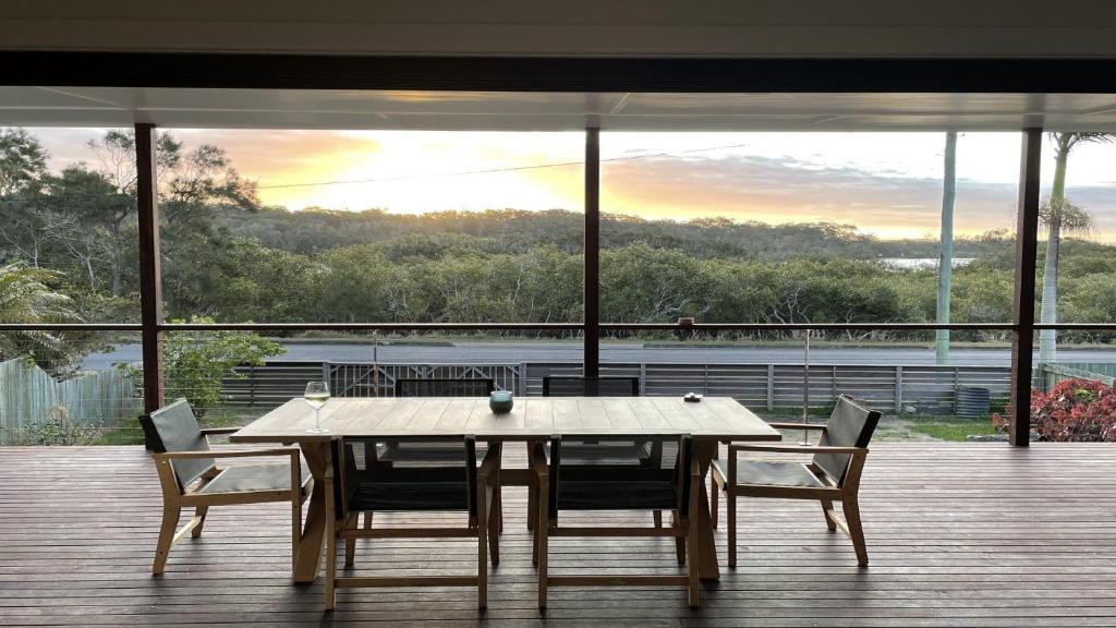 a table and chairs on a deck with a view at JJ s Holiday House in Wooli